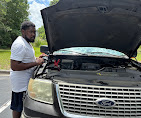 A&M Road Services technician jumpstarting a truck with the hood raised