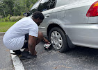 A&M Road Services technician changing a flat tire on a sedan roadside